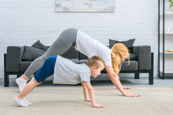 Side view of mother and son in adho mukha svanasana position on yoga mats - Photo, Image