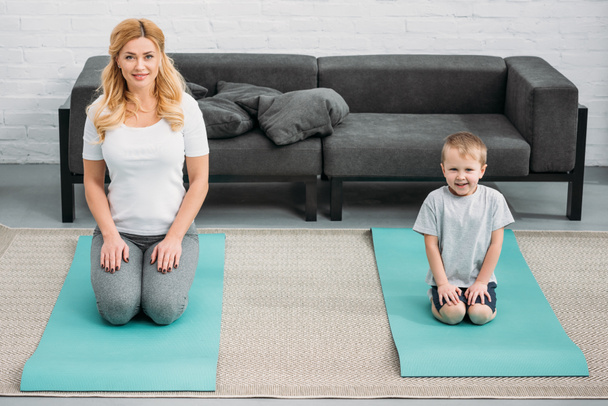Son and mother resting on fitness mats  - Photo, Image