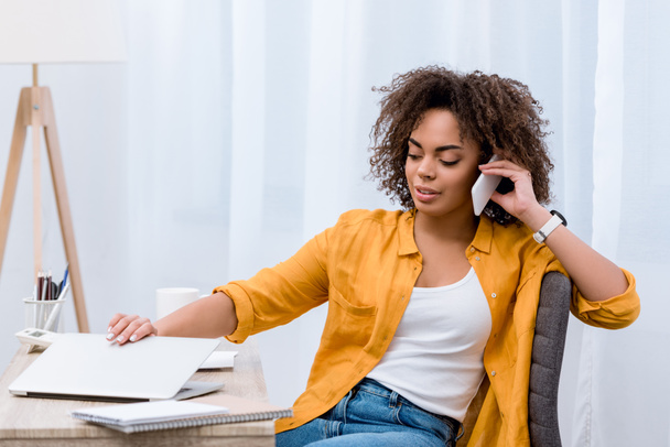 mujer joven afroamericana hablando por teléfono en el lugar de trabajo
 - Foto, imagen