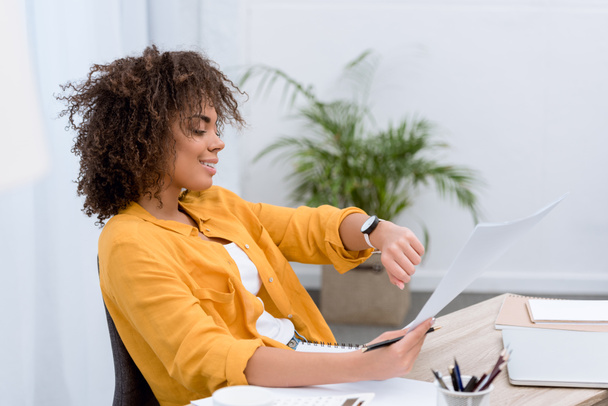 młody african american Kobieta w biurze, patrząc na zegarek - Zdjęcie, obraz
