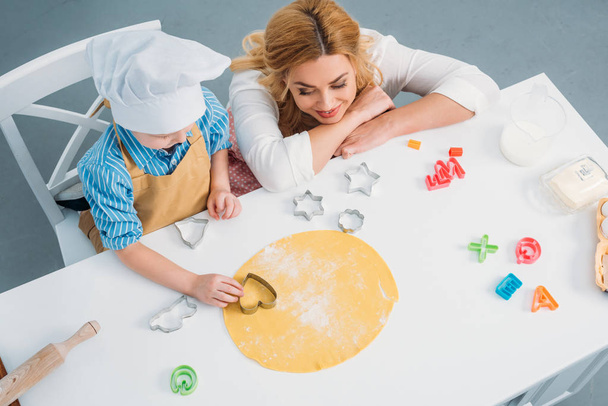 Vista de ángulo alto de la madre y el hijo utilizando molde de cocina en la masa
  - Foto, Imagen