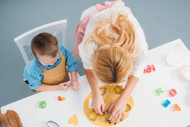 High angle view of son and mother using cooking molds  - Foto, afbeelding