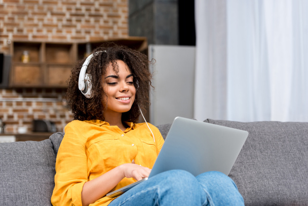 幸せな若い女性のラップトップの使用、自宅で音楽を聴く - 写真・画像