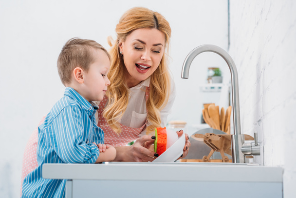 Tál-konyhai mosogatás anya és fia  - Fotó, kép