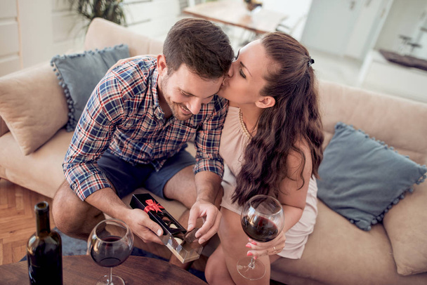 Nuori pari yhdessä istuu sohvalla ja juo viiniä
 - Valokuva, kuva