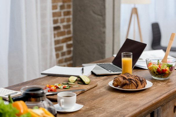 freelancer workplace at kitchen with food on table and laptop - Foto, Bild