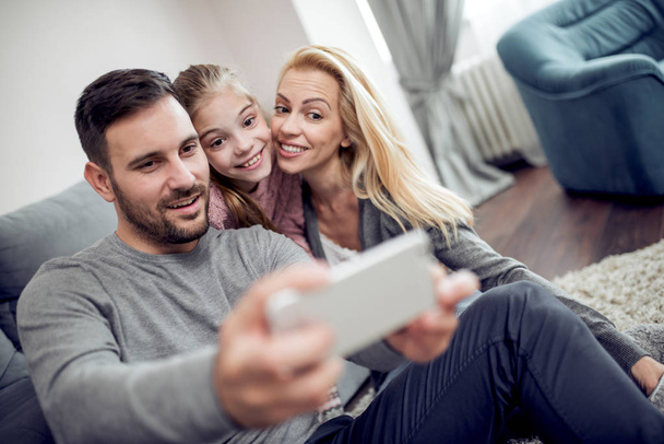 Mladé rodiny pořizování selfie doma v obývacím pokoji - Fotografie, Obrázek
