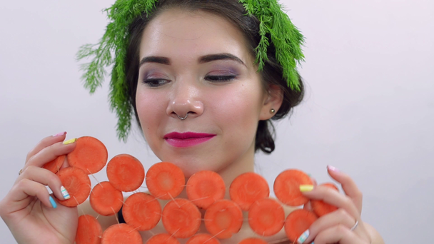 Chica con perejil verde en la cabeza, cubrir la cara por círculos de zanahoria. Posando. Sonríe
 - Metraje, vídeo