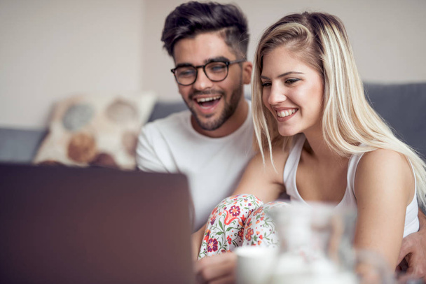 Young couple sitting in living room and using laptop - Foto, Imagem