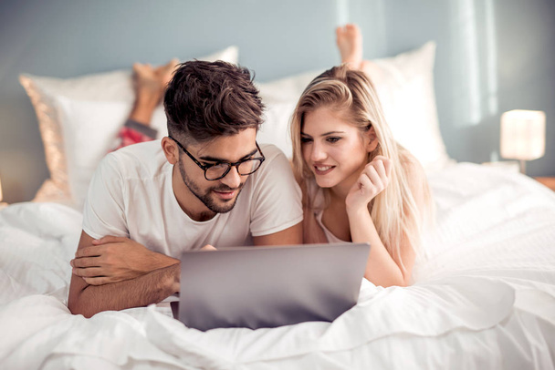 Férfi és nő élvez néz video-ra laptop-ban hálószoba - Fotó, kép
