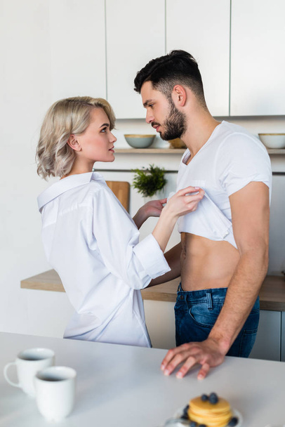 side view of seductive young couple looking at each other at morning in kitchen - Foto, Bild