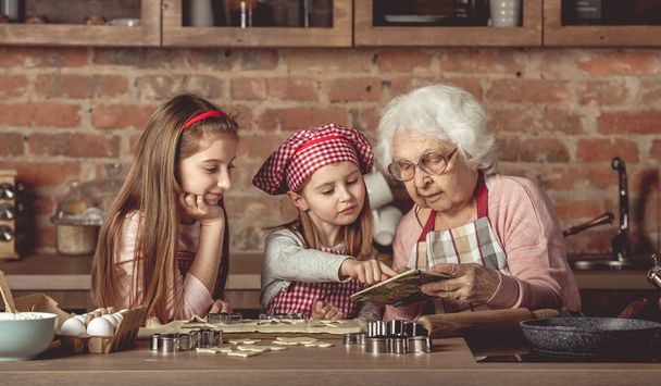 Grandma and granddaughters spreading dough - Foto, afbeelding