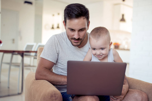 Jeune père et petit fils navigation ordinateur portable à la maison
 - Photo, image