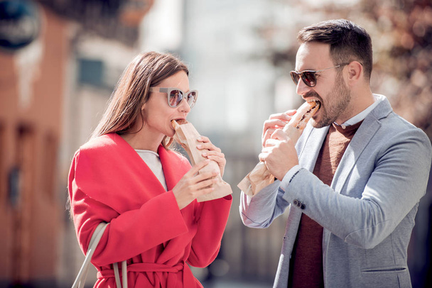 Casal comendo sanduíches nas ruas da cidade
 - Foto, Imagem