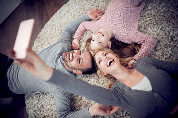 Young family taking selfie at home in living room - Foto, Bild