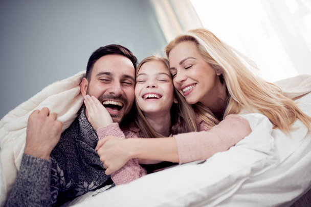 Οικογένεια βλέποντας τηλεόραση στο υπνοδωμάτιο και γέλιο  - Φωτογραφία, εικόνα
