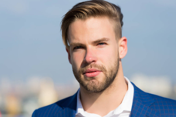 Man with bearded face on sunny outdoor. Businessman with stylish haircut on blurred sky. Business fashion, style and trend. Grooming and hair care in barbershop - Фото, зображення