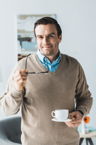 Attractive man holding glasses and cup of coffee - Foto, imagen