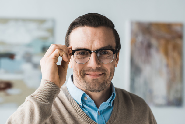 Smiling adult man fixing his eyeglasses - Photo, Image