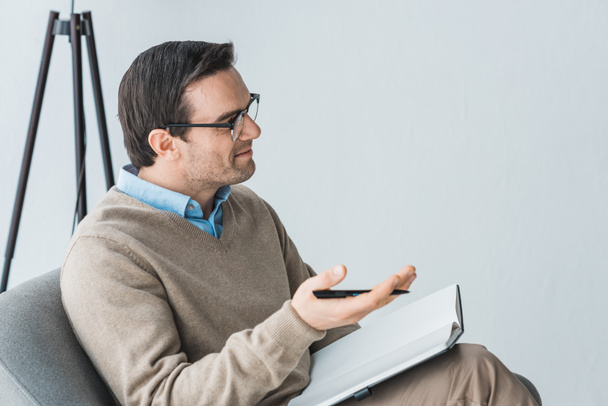 Male therapist in glasses listening to patient in office - 写真・画像