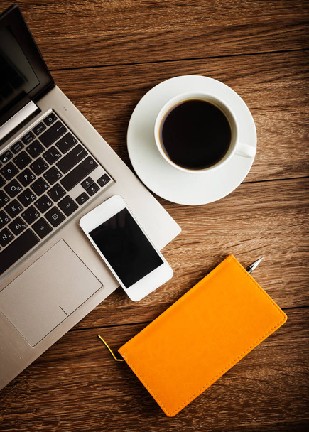 Escritorio de oficina con computadora portátil, planificador, teléfono inteligente móvil y taza de café
 - Foto, Imagen
