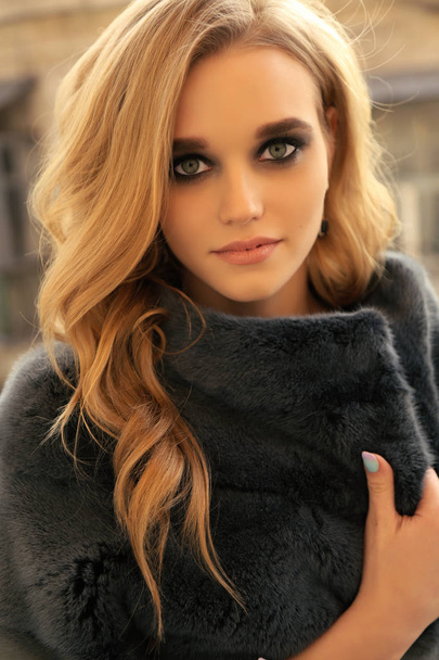 fashion outdoor photo of beautiful young woman with blond hair and evening maleup in elegant fur coat - Photo, image