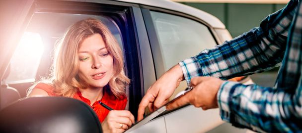 Woman sitting in the car and signing car rental agreement - Foto, immagini