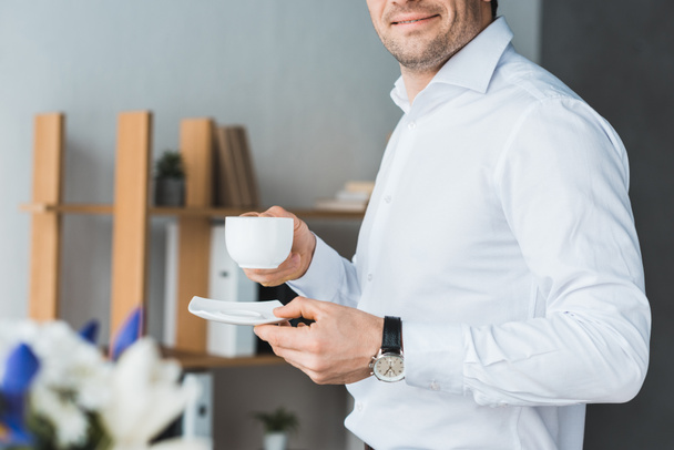 Close-up view of businessman holding cup with coffee in office - Photo, image