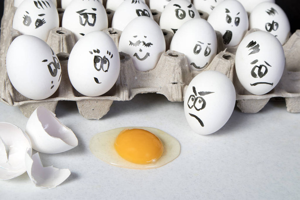 the Hen eggs in box. Eggs cover with drawings. Look like man face. Indignant eggs look at the broken egg. - Foto, Imagem