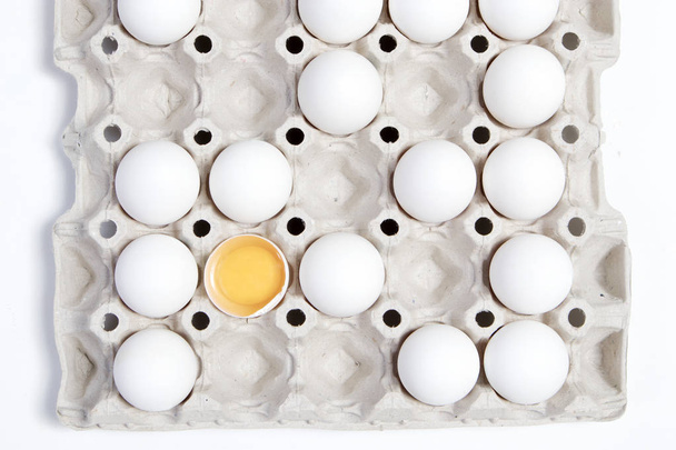 One broken egg with the other eggs in a cardboard box from the store. It looks like a chessboard. - Foto, Imagem