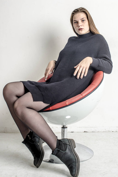 Young beautiful girl sitting in a gray long warm sweater - Valokuva, kuva