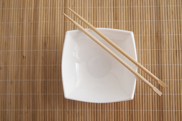 rectangular square white empty plate with chopsticks on a bamboo table  - Zdjęcie, obraz