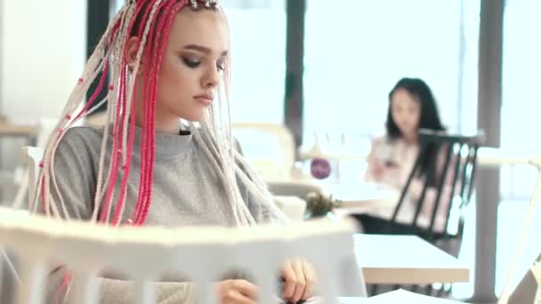 Młoda dziewczyna biodrówki zaglądać w menu w café - Materiał filmowy, wideo