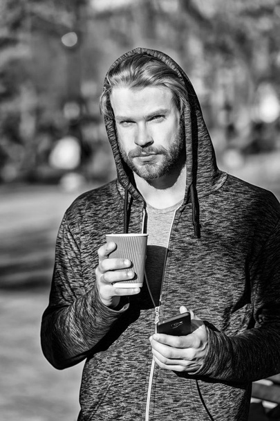 Man holding mobile phone and paper cup in park - Foto, Imagem