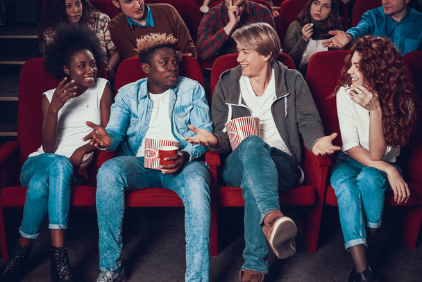 Two friends sit in front row at cinema and talk.  - Foto, afbeelding