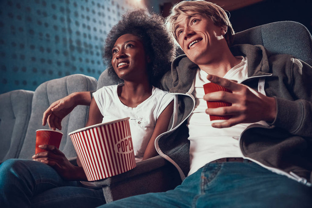 Multinational couple is watching comedy in cinema. - Zdjęcie, obraz
