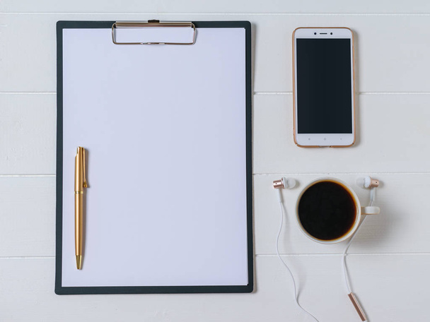 Caderno com caneta, café, smartphone e fones de ouvido em uma mesa de madeira escura. A vista de cima
. - Foto, Imagem