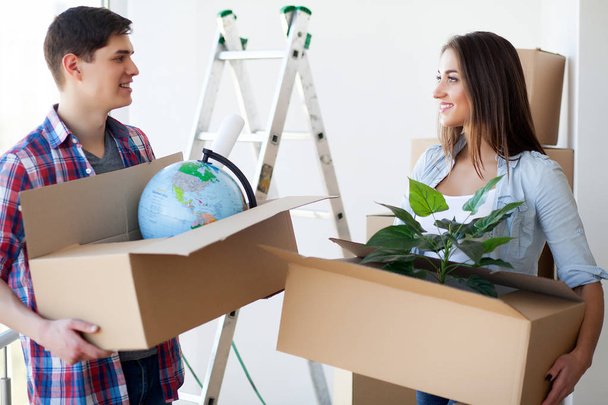 Ένα ζευγάρι με κουτιά κινείται προς ένα νέο σπίτι. Ακίνητα προς πώληση. - Φωτογραφία, εικόνα