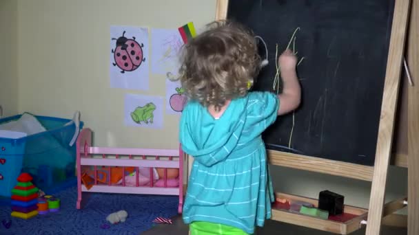 lovely toddler girl drawing on chalkboard at home - Footage, Video