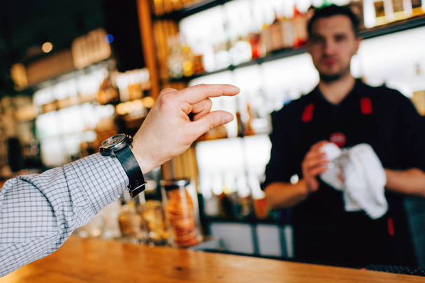 Close up of a customers hand showing a portion of alcohol to barman. And this potion should be poured into the glass. It is very small. - Foto, afbeelding