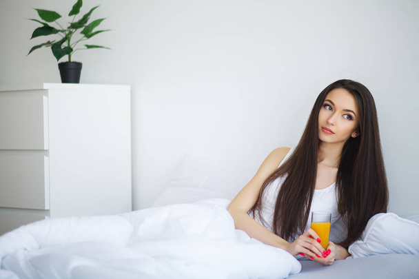 Jonge vrouw genieten van een glas jus d'orange in de ochtend als s - Foto, afbeelding