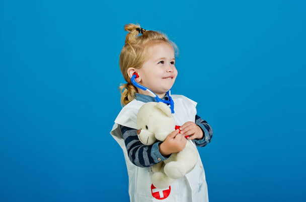 Happy boy in doctor uniform examine toy pet with stethoscope - Photo, Image
