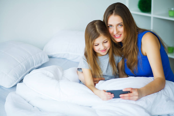 Mother and daughter listening to music in bed - Foto, Bild