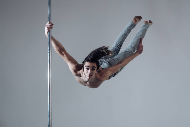 Guy makes figure on pole, fly in air. Work out. - Photo, Image
