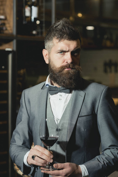 Confident winemaker in romantic atmosphere of cigar club. cigar club, serious winemaker with glass in business suit. - Fotó, kép