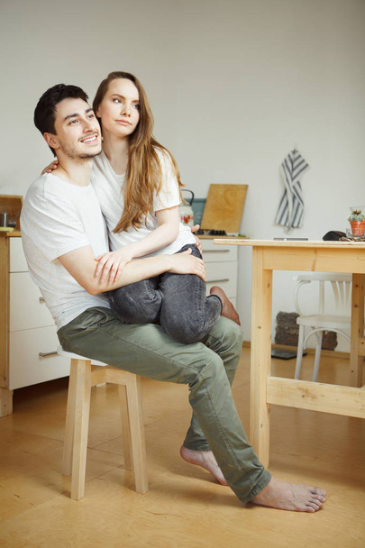Woman sitting on her boyfriend legs in the kitchen. - Foto, imagen