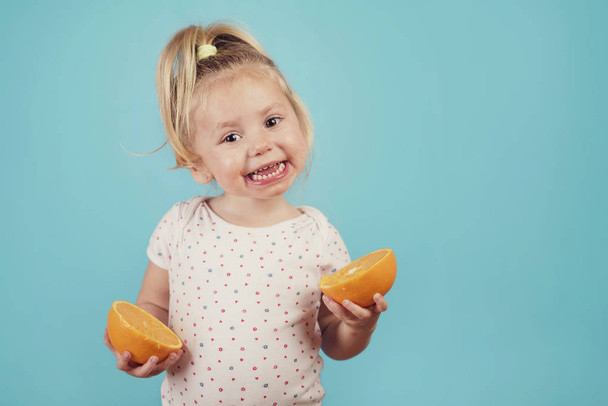 smiling baby with an orange on blue background - Foto, Bild