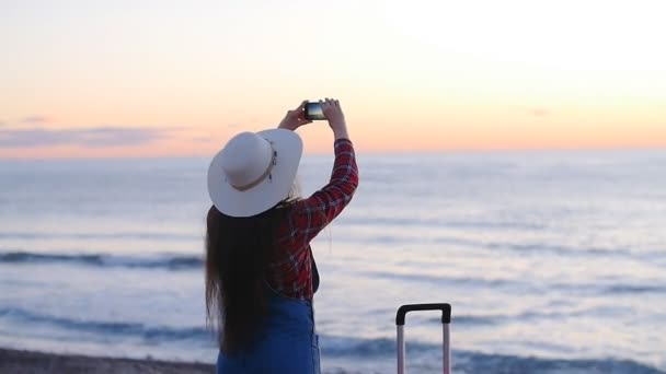 Jovem mulher tirando fotos na praia durante o pôr do sol ou nascer do sol
 - Filmagem, Vídeo
