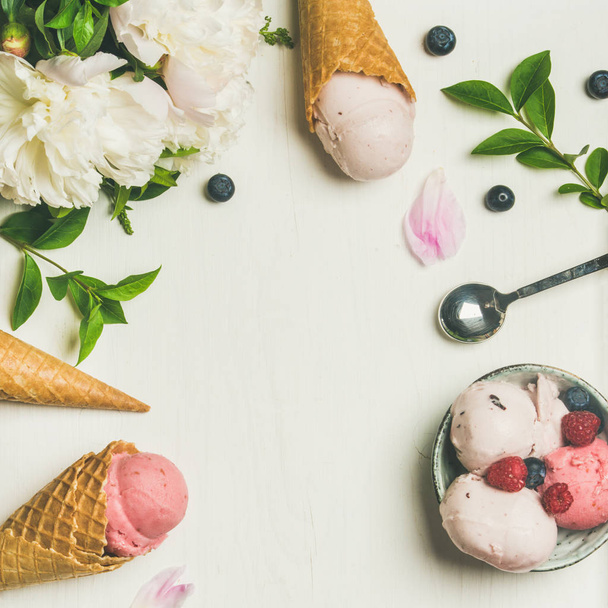 Pink strawberry and coconut ice cream scoops, sweet cones and peony flowers bouquet over white background - Zdjęcie, obraz
