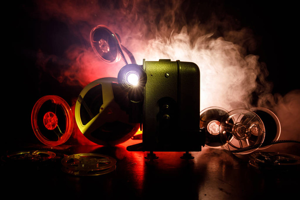 Old style movie projector, close-up. Film projector on a wooden background with dramatic lighting and selective focus. Movies and entertainment concept - Photo, Image